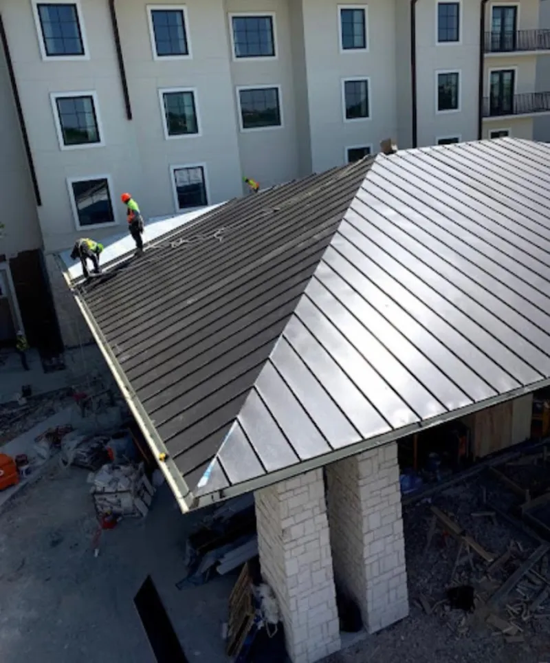 Crew installing standing seam metal roof panels on a commercial project in Savage